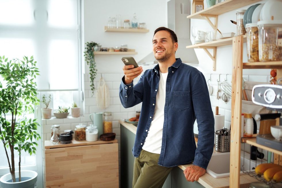 Young handsome man controlling security system with mobile app stock photo