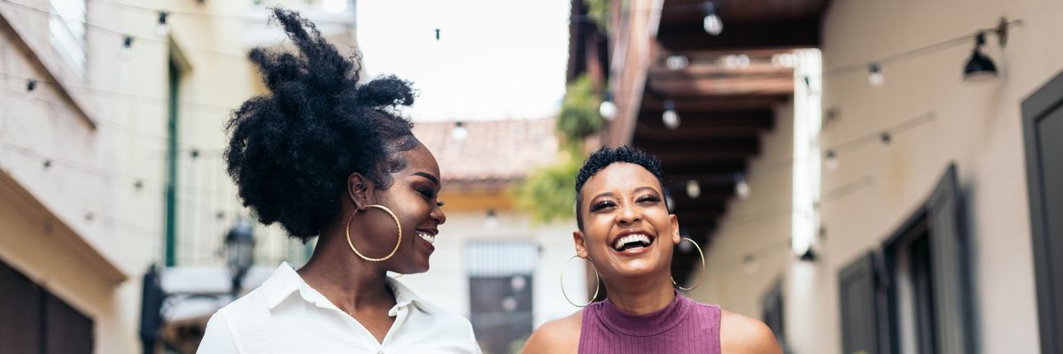Stylish black women friends having fun and laughing a lot walking down the street