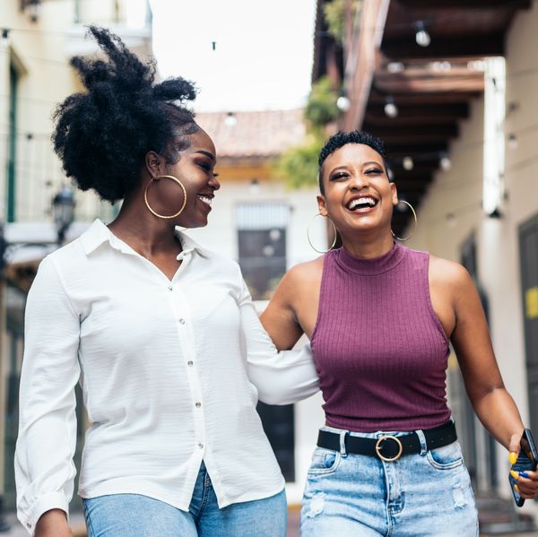 Stylish black women friends having fun and laughing a lot walking down the street