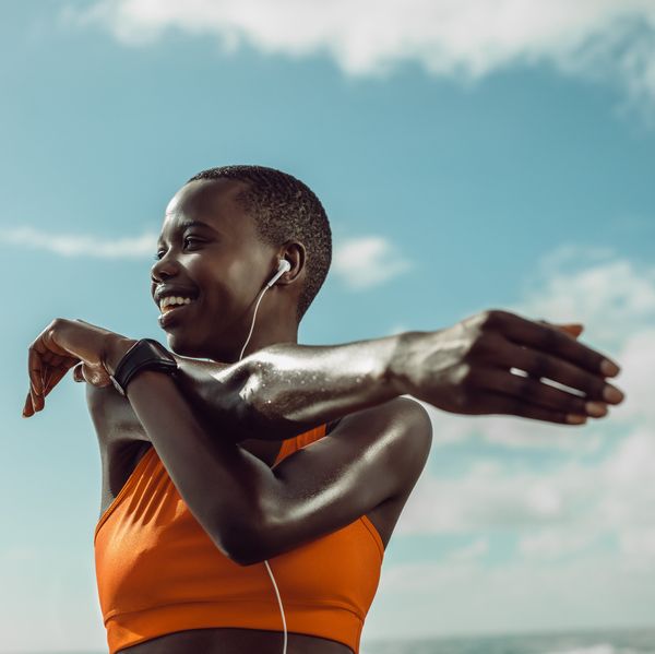 Black woman stretching at the beach during a morning workout during The Great Lock In reset