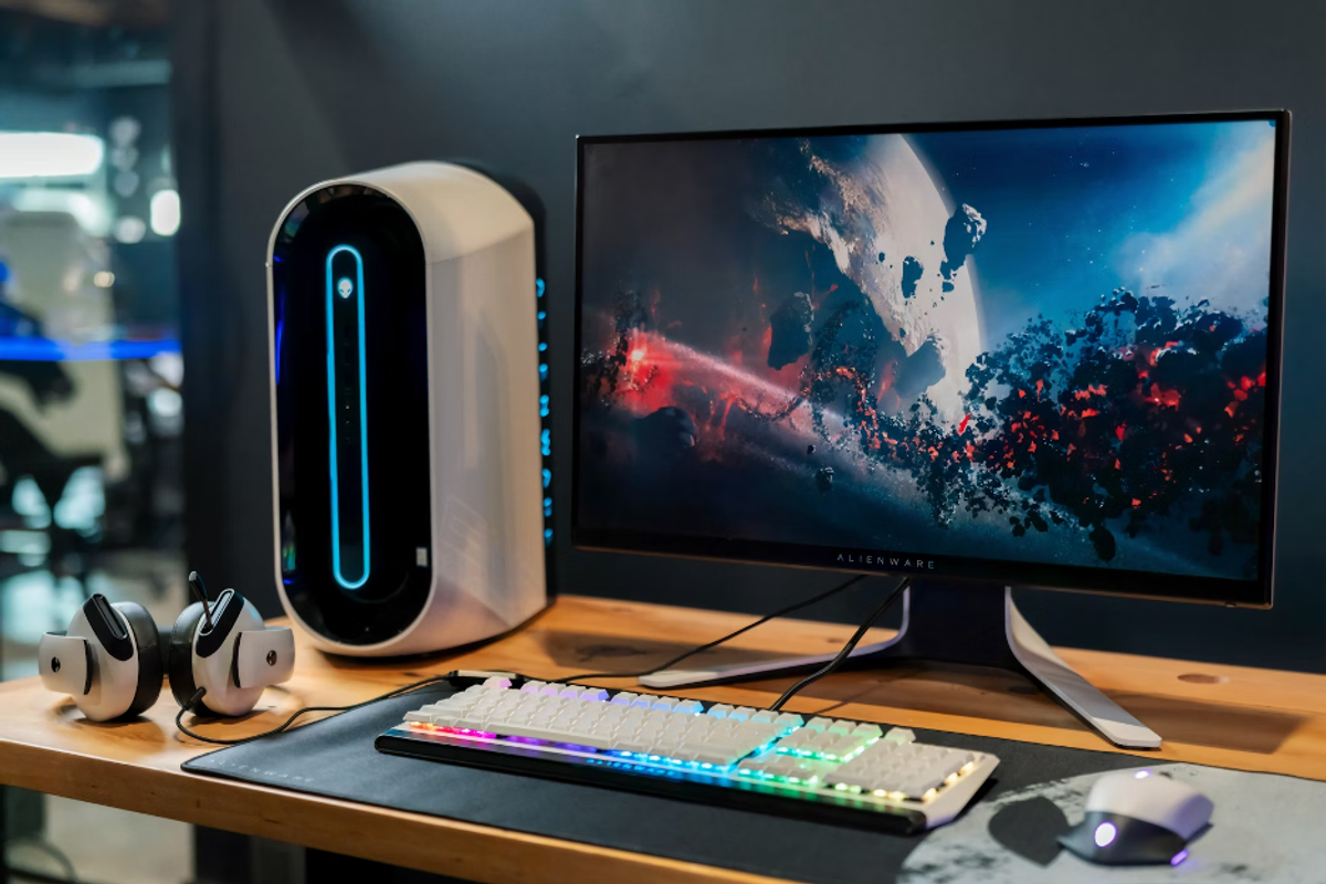 photo of a home office with keyboard, moust, speaker and tower computer and screen