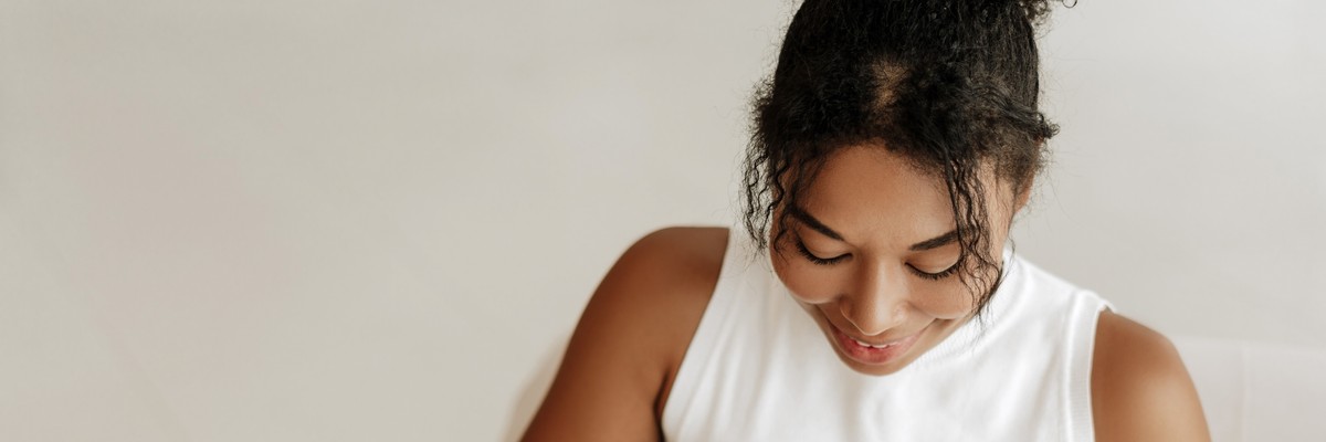 Young woman smiling while eating yogurt at home, symbolizing probiotics and vaginal health for preventing yeast infections after sex.