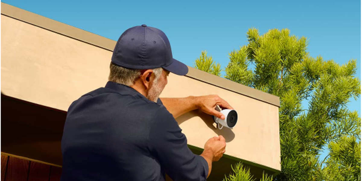 A photo of a man installiing Nest Cam Outdoor on a house.