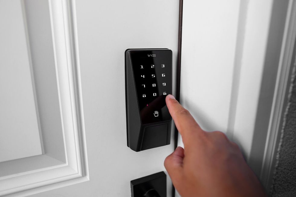 a photo of a person using their finger to enter code on Wyze Palm Lock