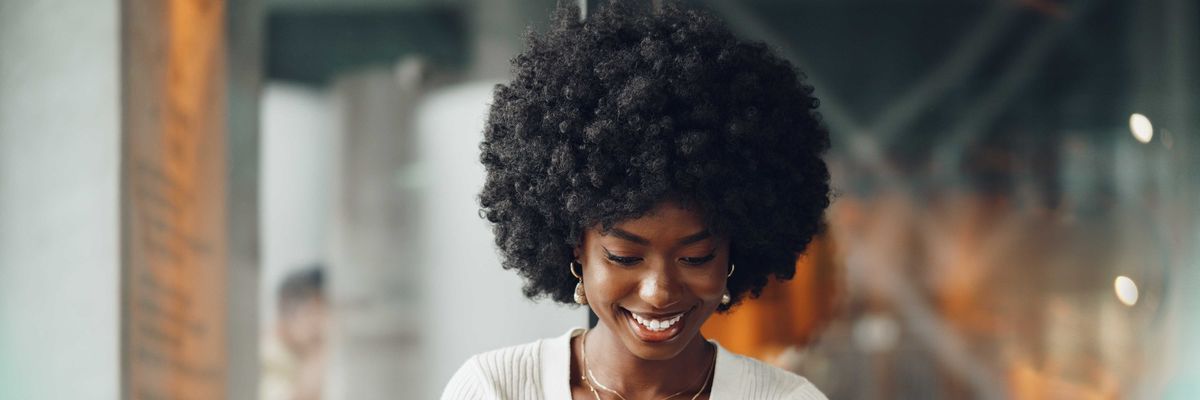 Portrait of a beautiful young african woman using her cellphone in a cafe