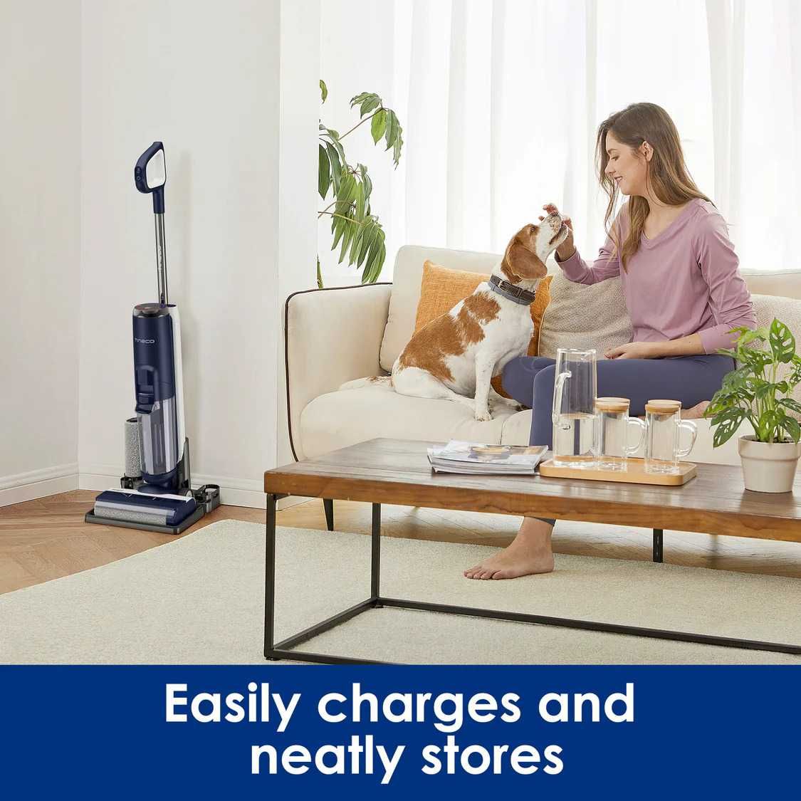 a woman sitting on a couch with her dog and a Tineco Dry Vacuum is in the corner.