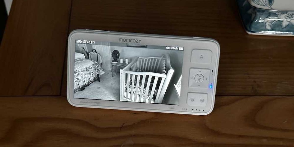 a photo of Momcozy baby monitor showing video from camera in baby's bedroom during the day.