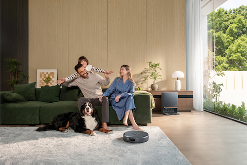 photo of a family sitting on a couch with Narwal robot vacuum cleaning the rug