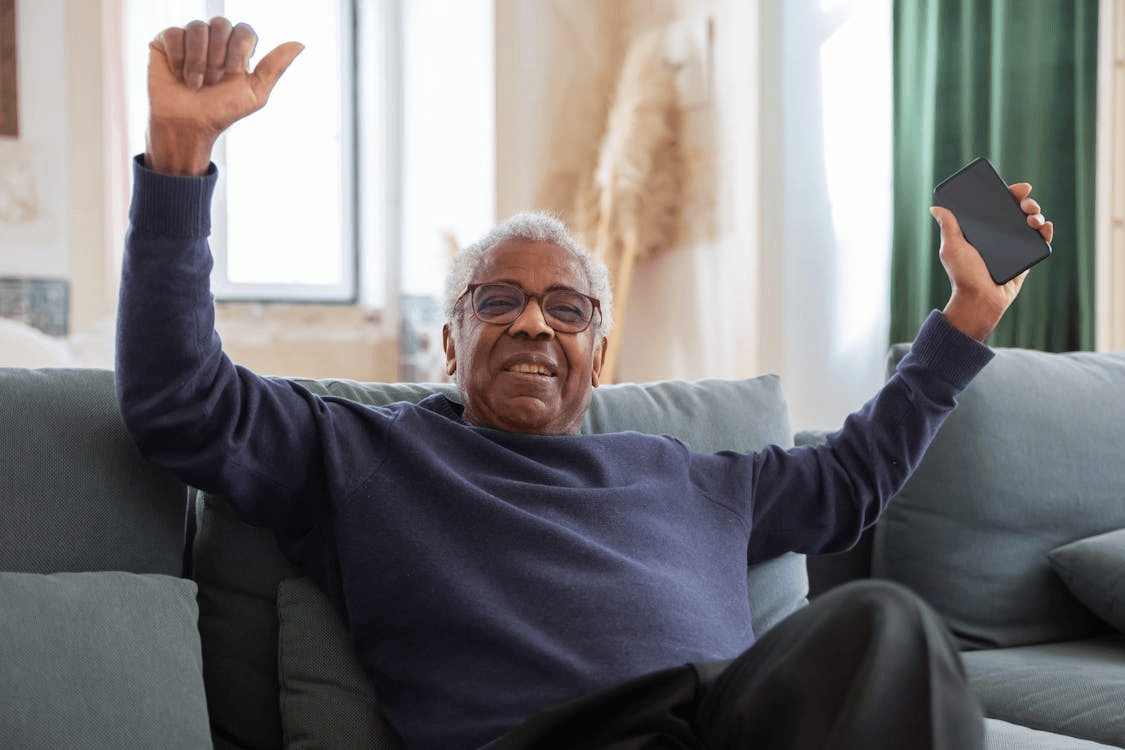 photo/elderly-man-sitting-on-sofa-while-holding-a-cellphone