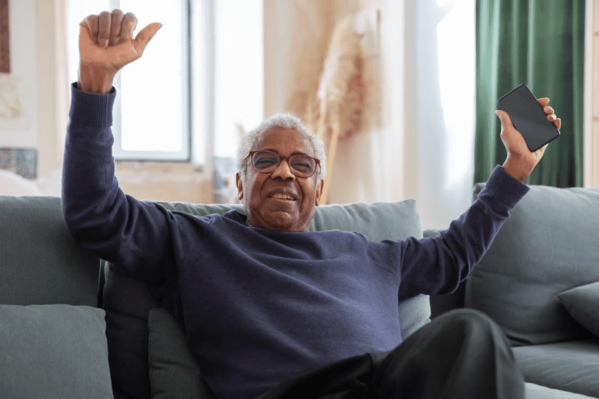 photo/elderly-man-sitting-on-sofa-while-holding-a-cellphone