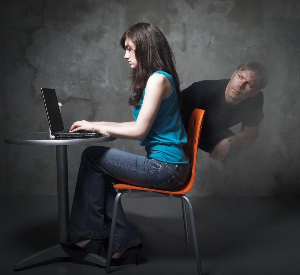 a woman on a laptop with a man peeking over her shoulder to see her logging in