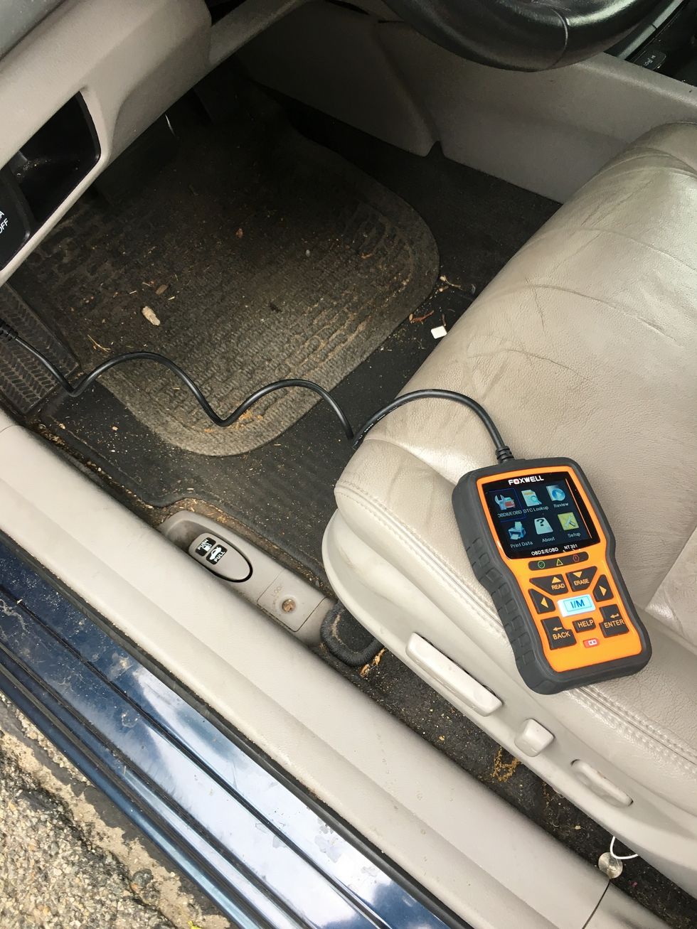 photo of foxwell code reader connected to a car's obd port.