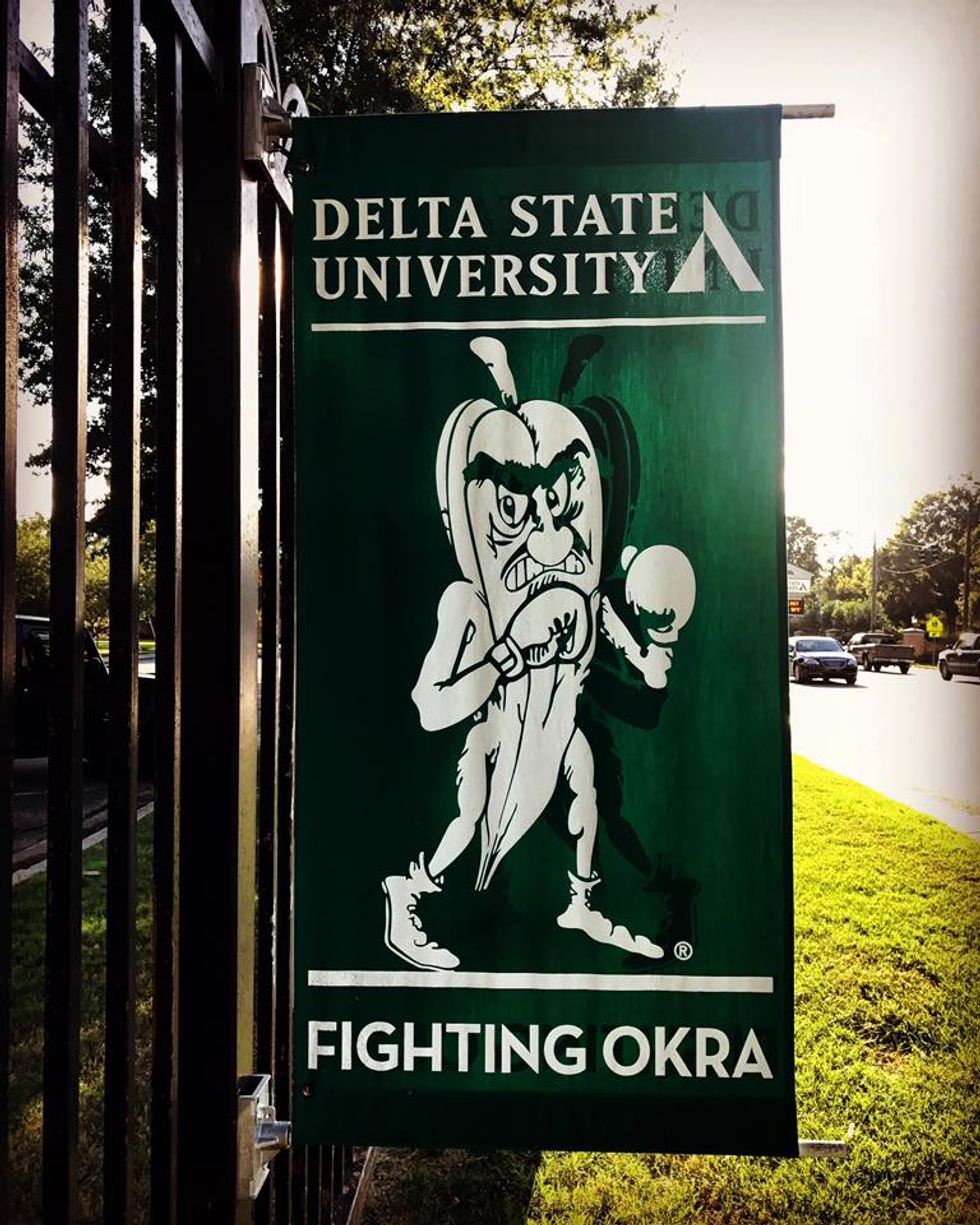 A green flag with the Delta State Fighting Okra mascot in the middle