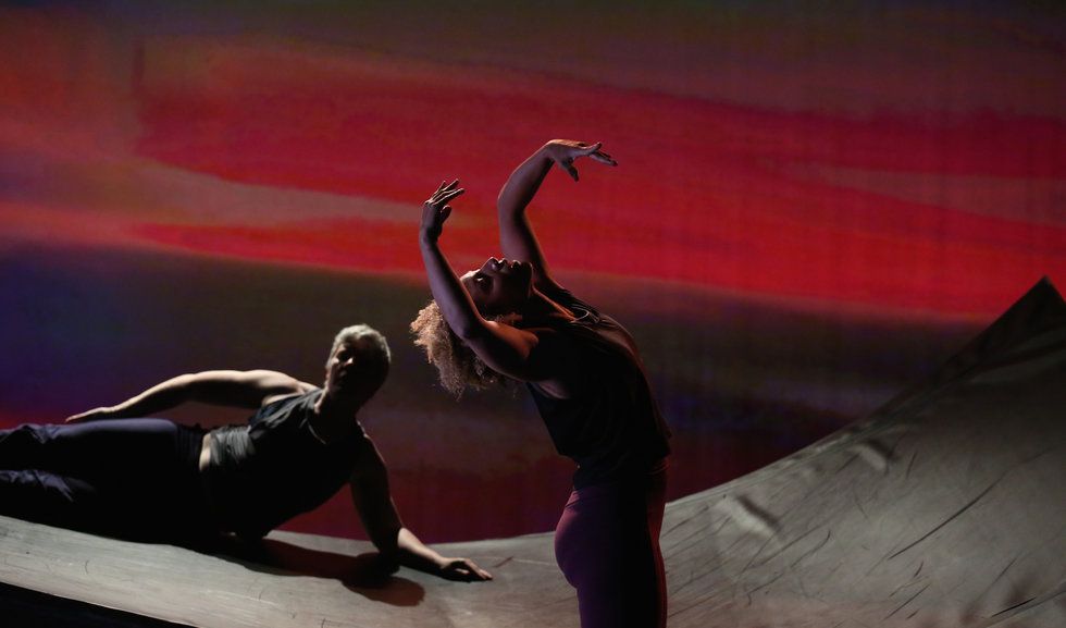 Alice Sheppard and Laurel Lawson in DESCENT. Alice is foreground, reaching up to the sky. Laurel is further back on the ramp, lying on her side and looking at Alice. Photo courtesy MANCC.