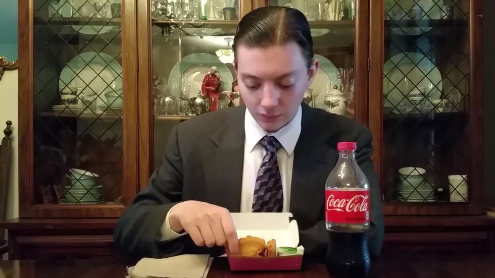 college student eating fast-food mcdonald's chicken nuggets and coke