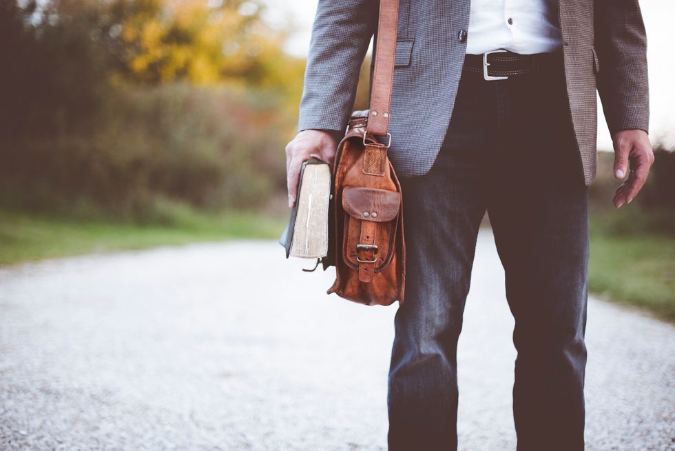Man in dress clothes holding a bag and book