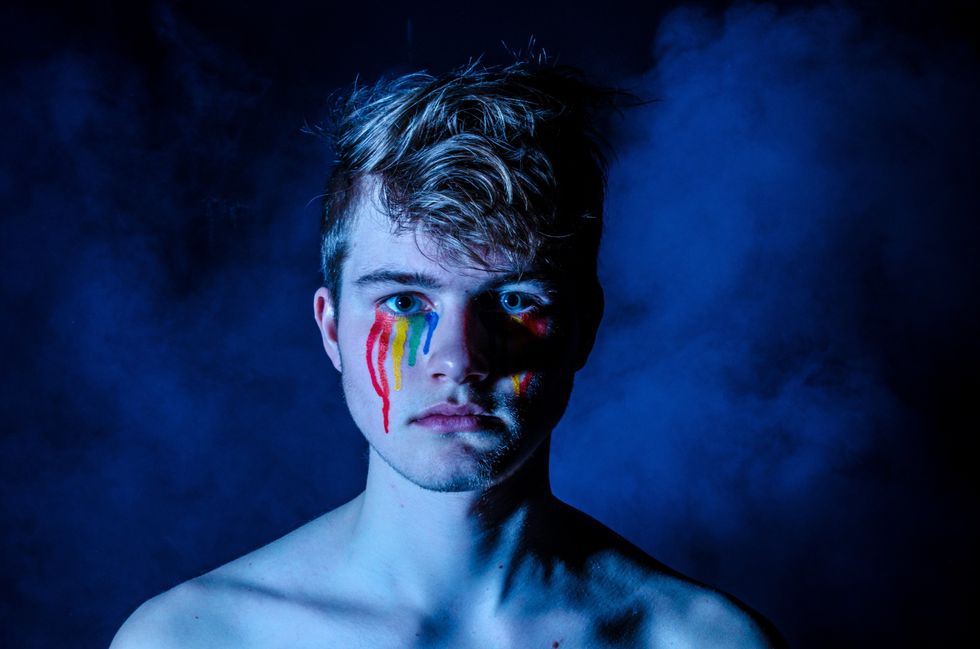 Boy crying rainbow colors with a blue filter over the whole image