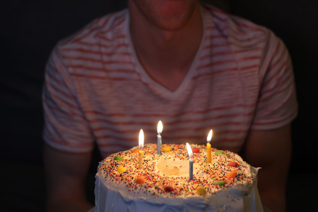 Guy holding birthday cake with four candles in it