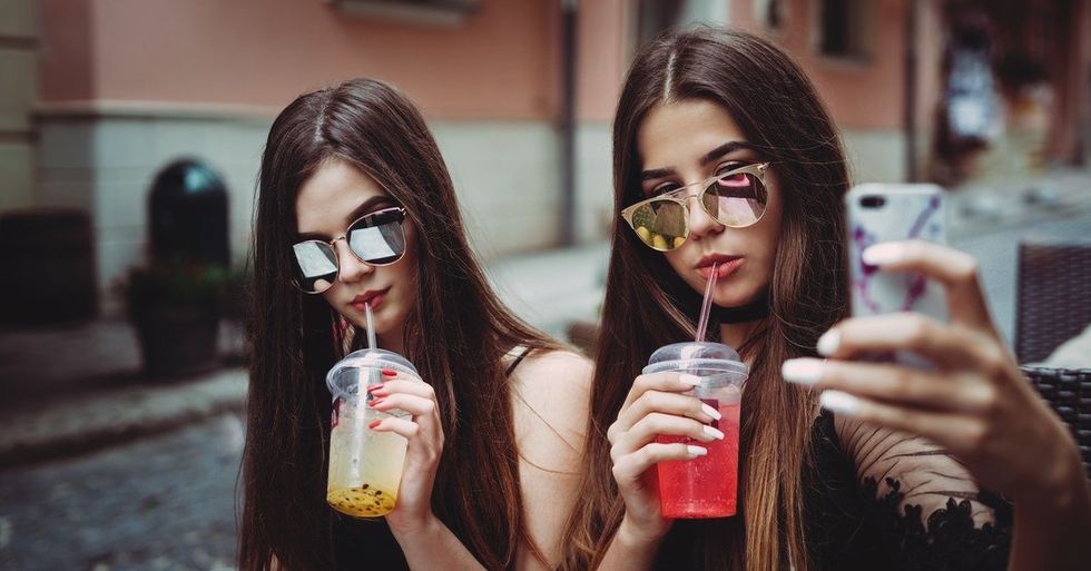 2 girls with glasses and drinks taking a photo together