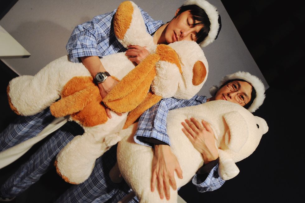 Two Japanese men in sleep clothes with teddy bears.