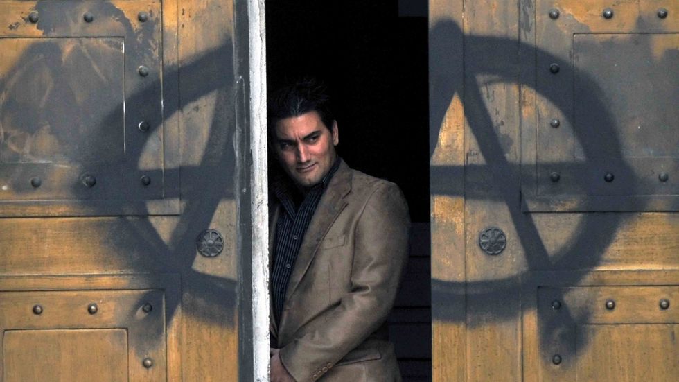 A man pears out from the door of the Bank of Greece marked with an A for anarchy. (LOUISA GOULIAMAKI/AFP/Getty Images)