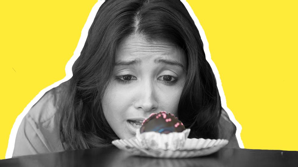 A woman with sugar cravings looking at cupcake. Photo: Shutterstock