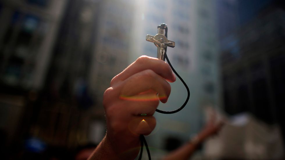 A Christian person holding a cross. (Photo: Eric Thayer/Getty Images)