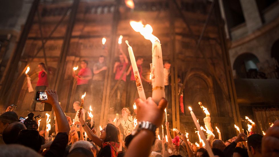 Christian Orthodox worshipers hold candles lit from a flame that emerged from the tomb believed to be of Jesus Christ. (Photo by Ilia Yefimovich/Getty Images)