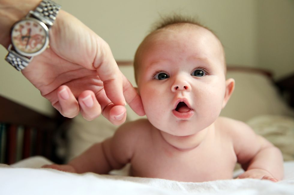 A man with a watch on brushes an infant's cheek with his finger.