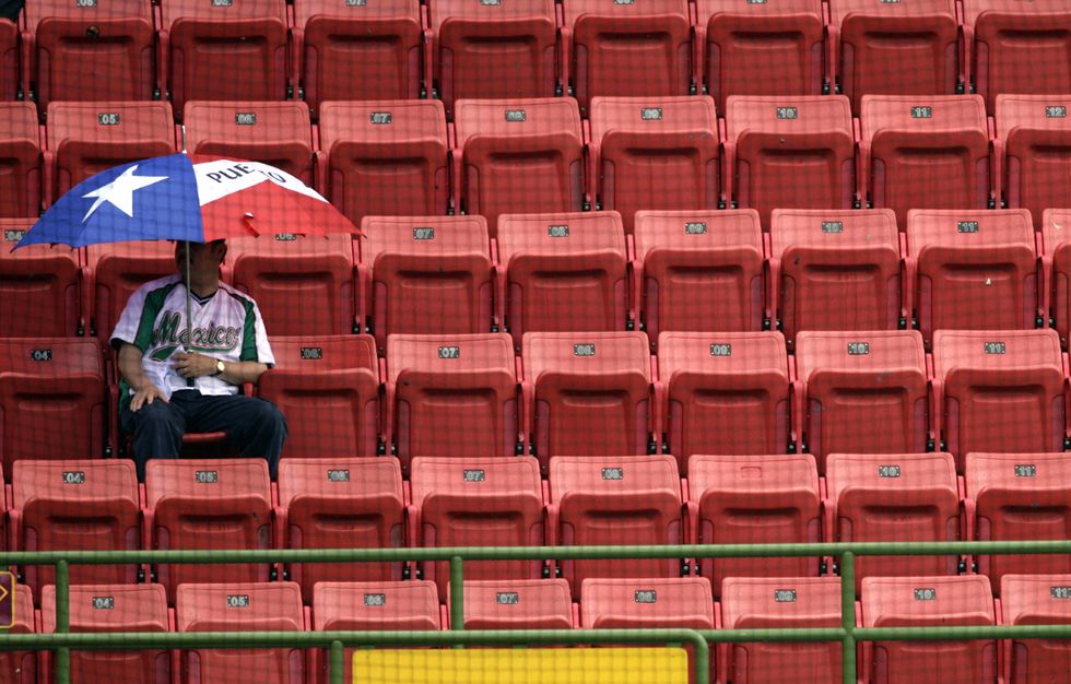 A young man sits by himself in a stadium.
