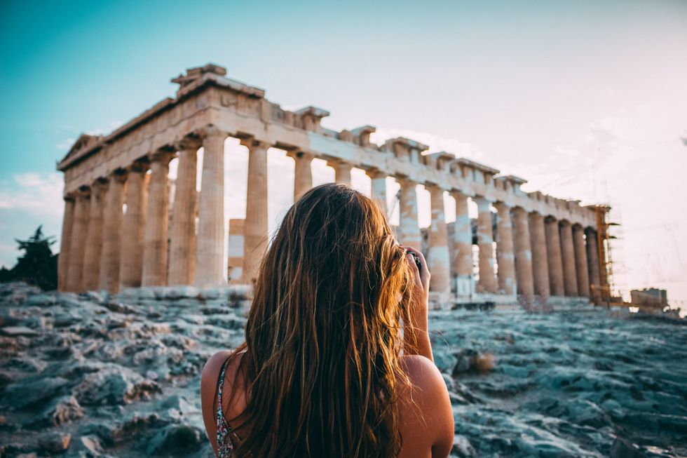 Taken in Athens, Greece, the photo shows a woman with her back turned to the camera and facing an ancient building.