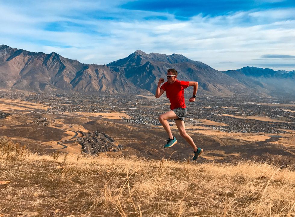 Male runner running up a hill with mountains in the background
