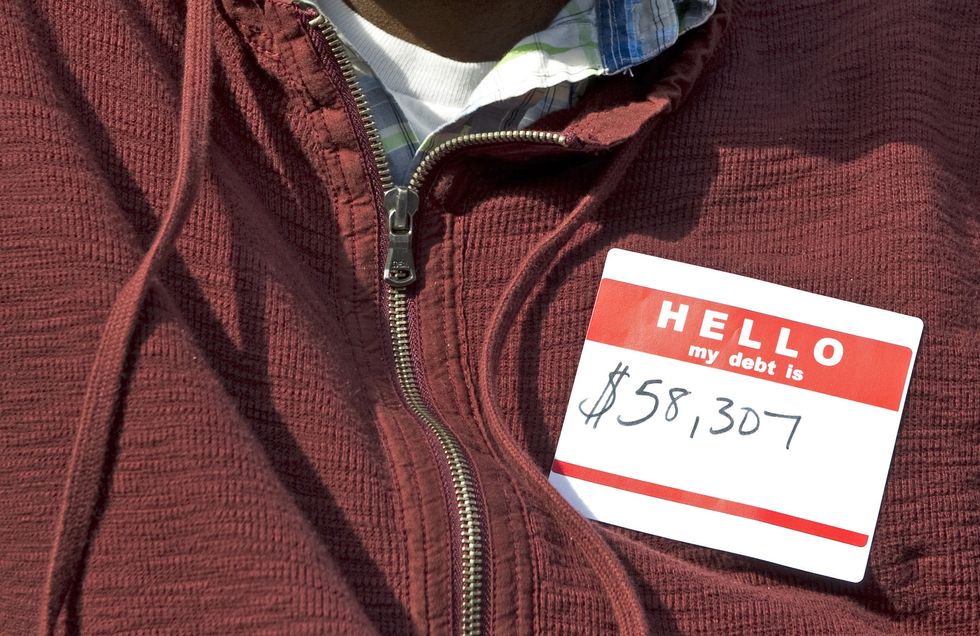 A man with an introduction sticker on his chest that reads: "Hello, my student debt is: $58,307"