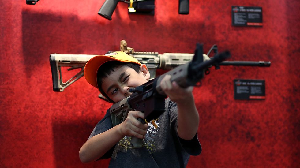 A young boy holding and aiming a gun.