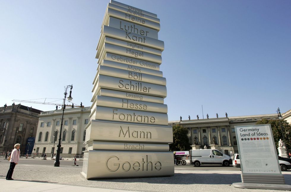 A woman looks at a giant sculpture featuring a pile of books by famous German writers and philosophers opposite Berlin's Humboldt University.