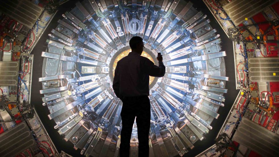A visitor takes a phone photograph of a large back lit image of the Large Hadron Collider (LHC) at the Science Museum's 'Collider' exhibition in London, England. (Photo by Peter Macdiarmid/Getty Images)