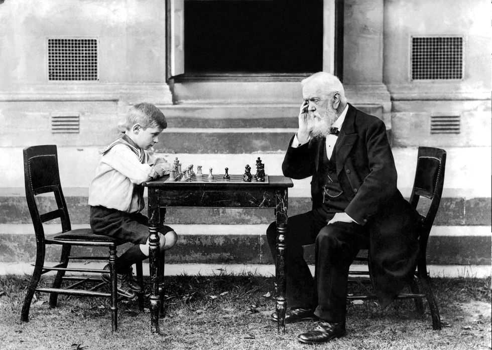 a young boy plays chess with an old man