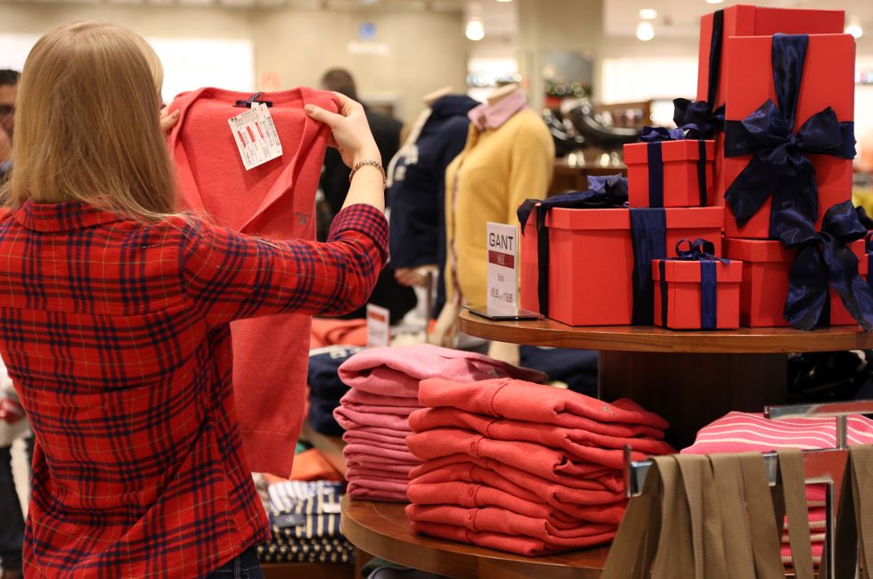 Lady holding up a sweater in a store.