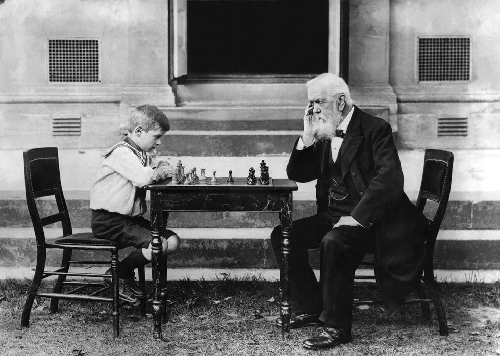 old man playing chess with a child.