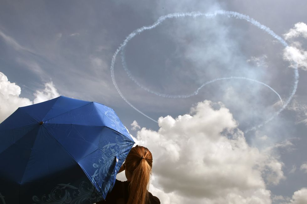 Girl with a blue umbrella sees a Yin-Yang in the sky.