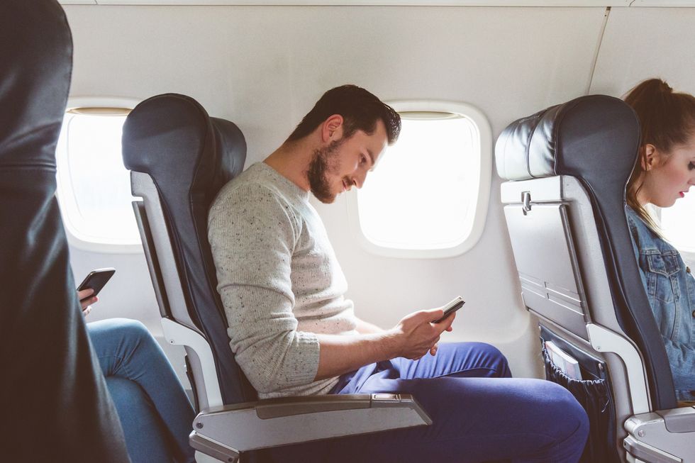 picture of man on airplane looking at his smartphone