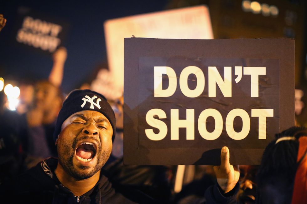 A Black Lives Matter protester holds a sign that reads 'Don't Shoot'
