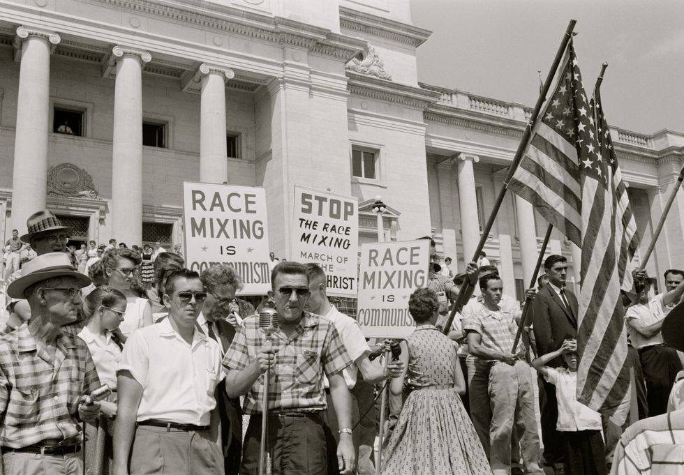 UNITED STATES - CIRCA 1959: people holding signs and American flags protesting the admission of the 'Little Rock Nine' to Central High School.