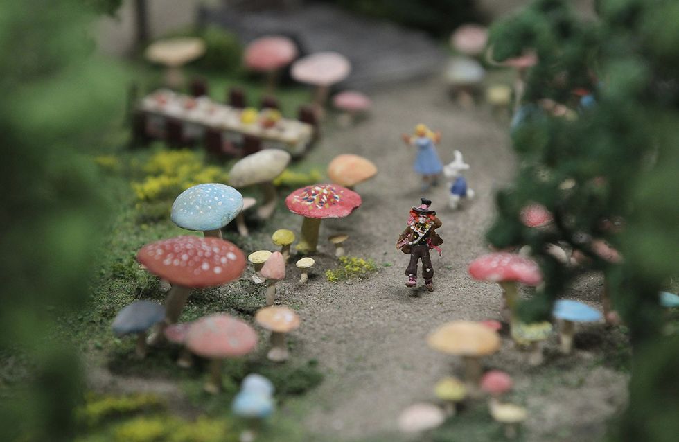 A miniature version of the Madhatter walks among rabbits and magic mushrooms from Alice in Wonderland.