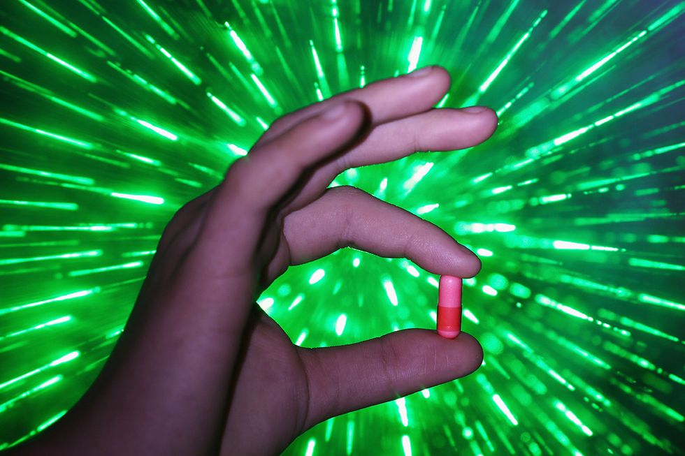 A pill with a mystical aura held in someone's hand.