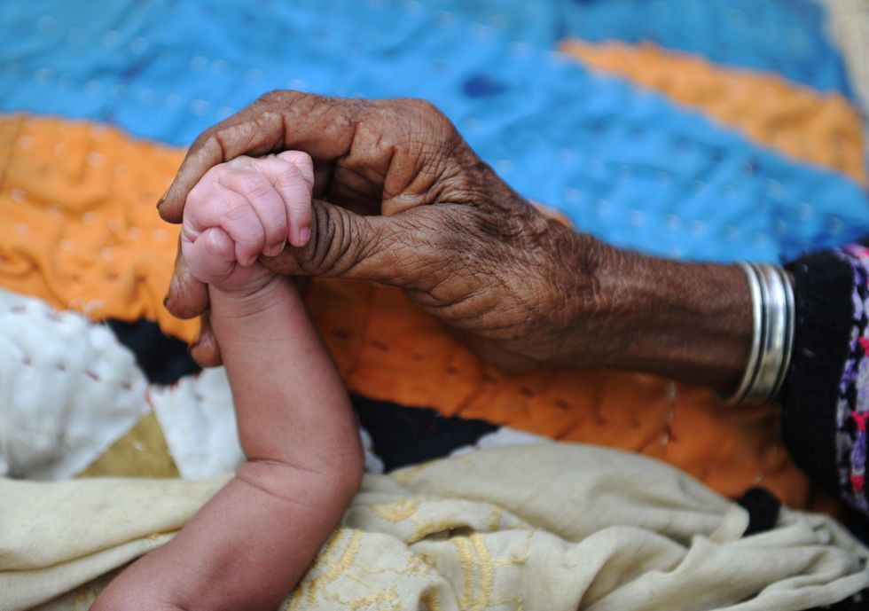 Grandmother and a newborn holding hands.