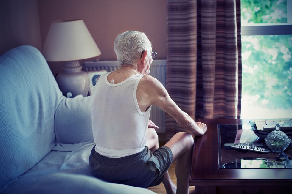 Old man sitting on a sofa looking out window