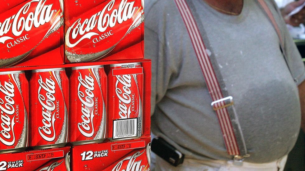 A heavyset man passes cartons of Coca-Cola displayed in a grocery store. (Tim Boyle/Getty Images)