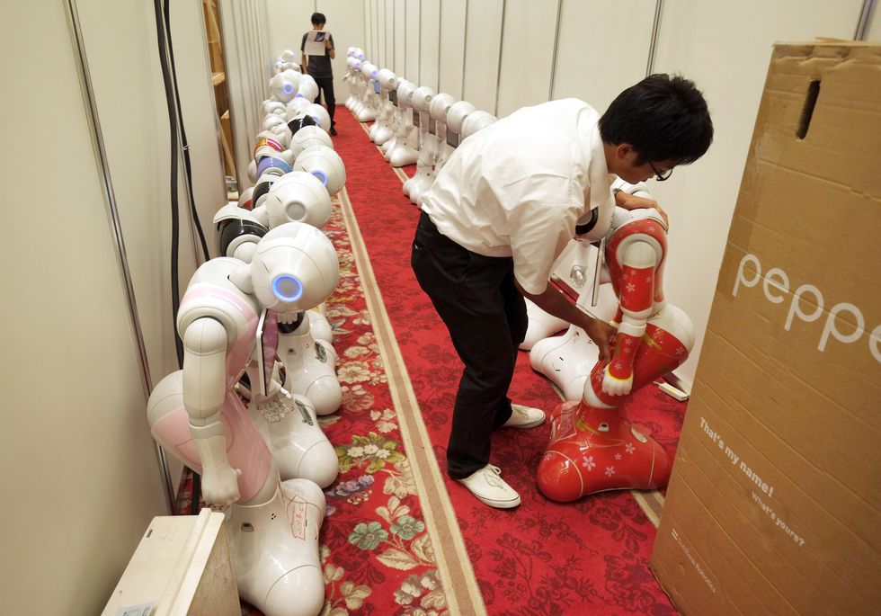 A worker arranges Japan's telecom giant Softbank's 'Pepper' humanoid robots in a hotel in Tokyo.