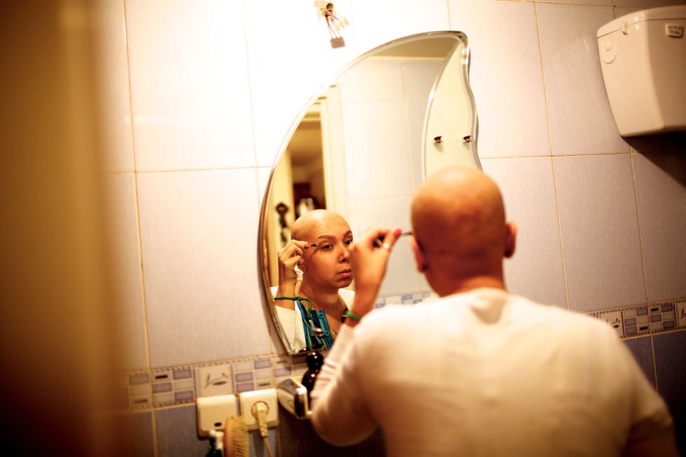 Woman with cancer looks in the mirror.